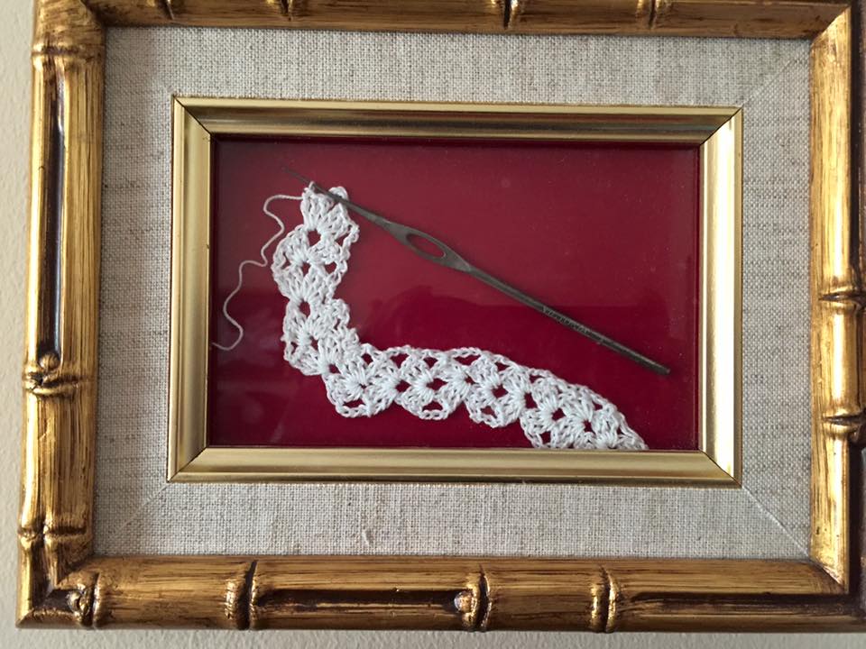 A crochet hook and chain framed.